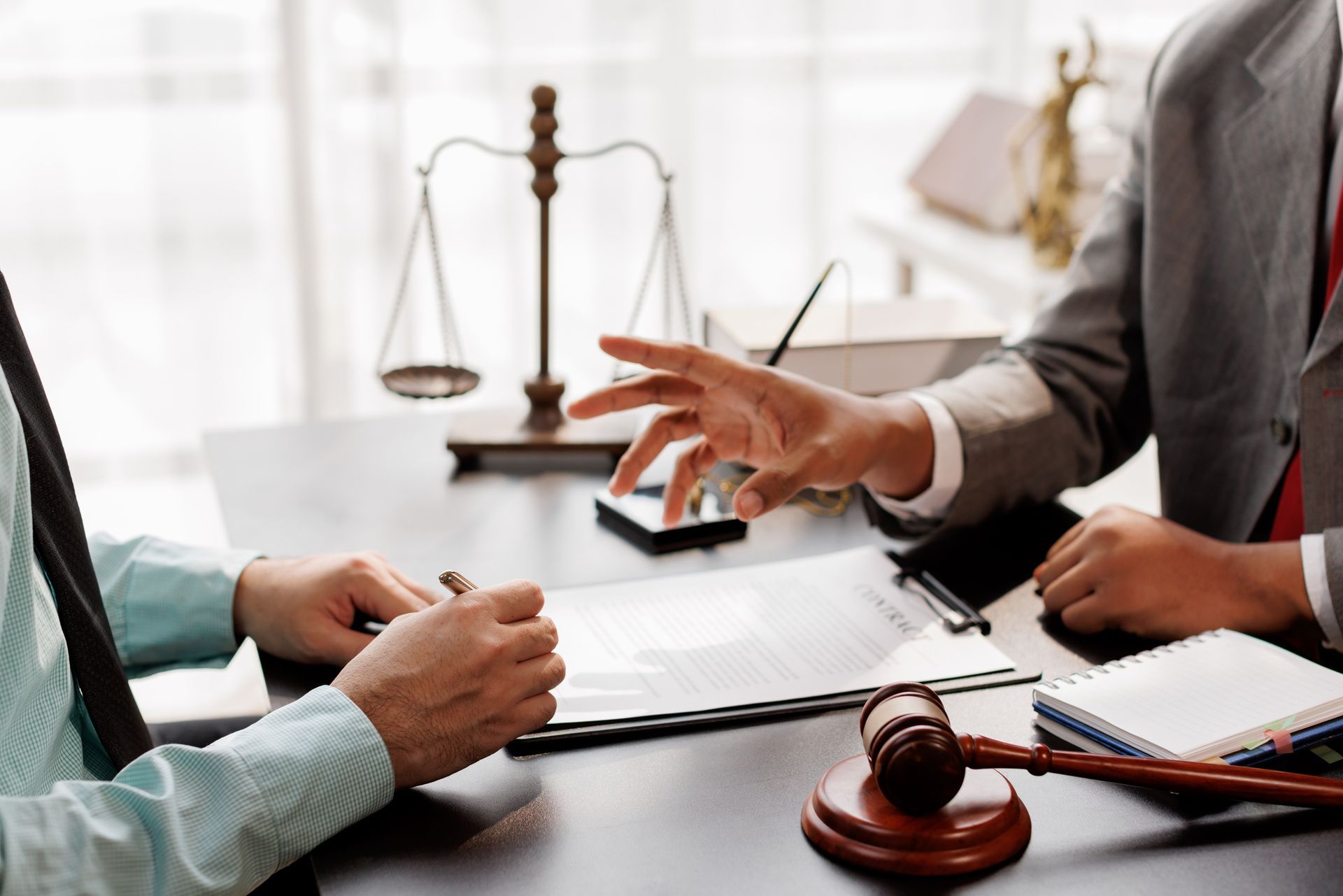 Lawyers in a meeting discussing documents, with a gavel and scales of justice on the table