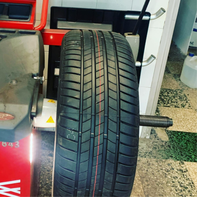 Primo piano di uno pneumatico per auto montato su un'equilibratrice in un'officina meccanica.