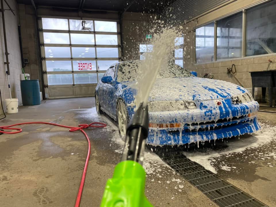 A blue car is being washed with foam in a car wash.
