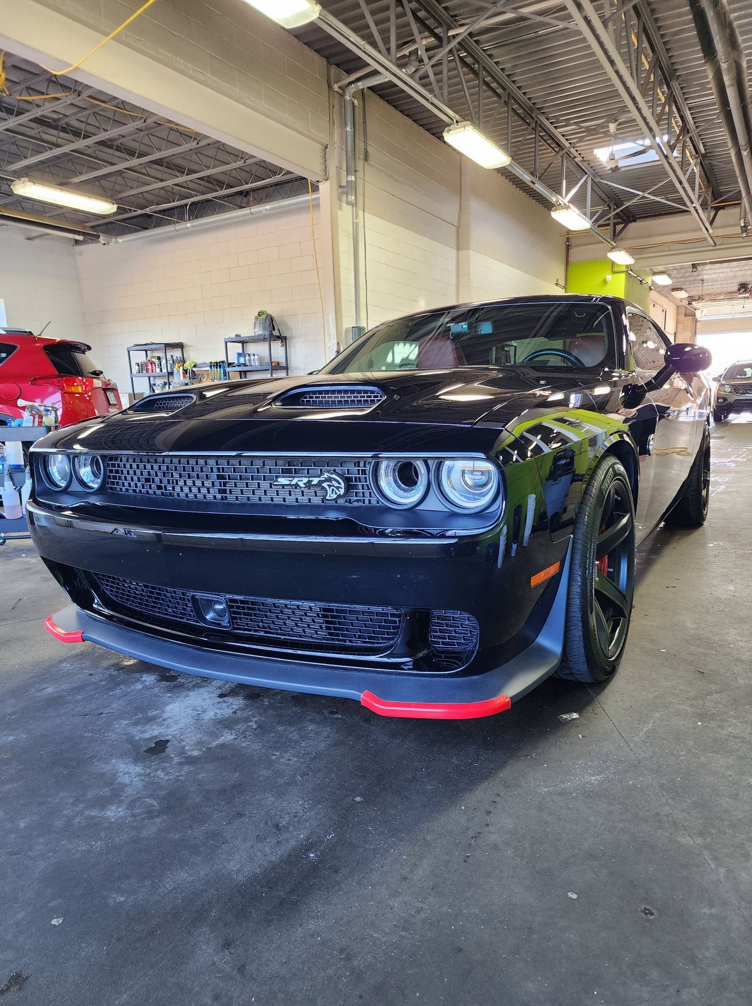 A black dodge challenger is parked in a garage.
