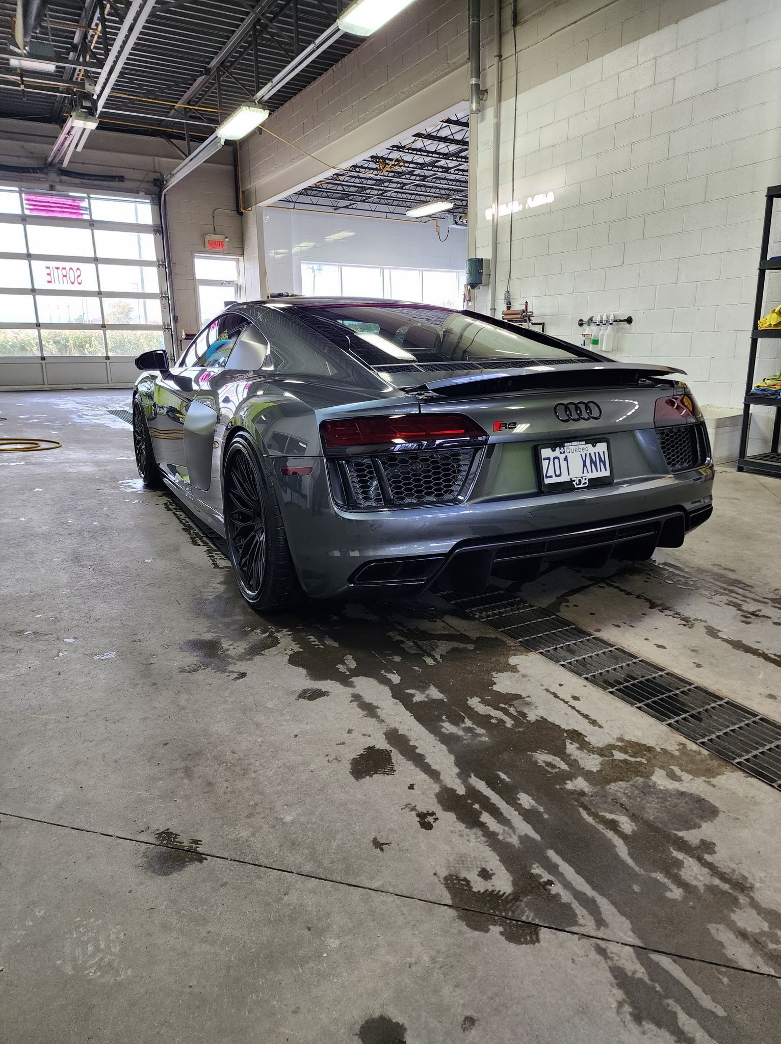 A silver audi r8 is sitting in a garage.
