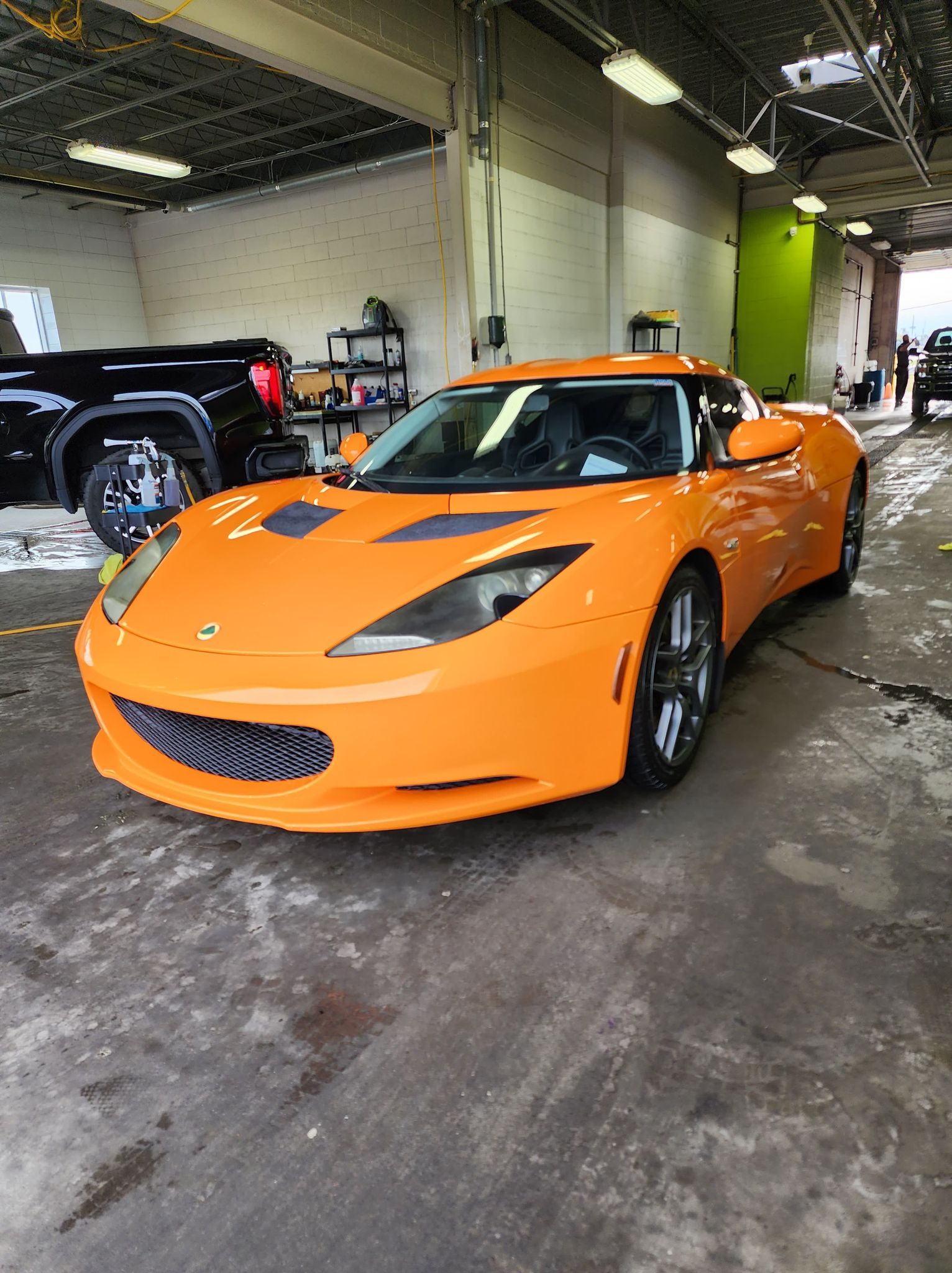 An orange sports car is parked in a garage.