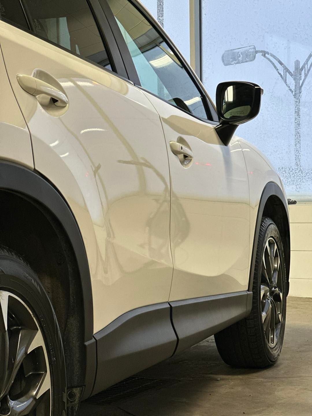 A white car is parked in front of a window