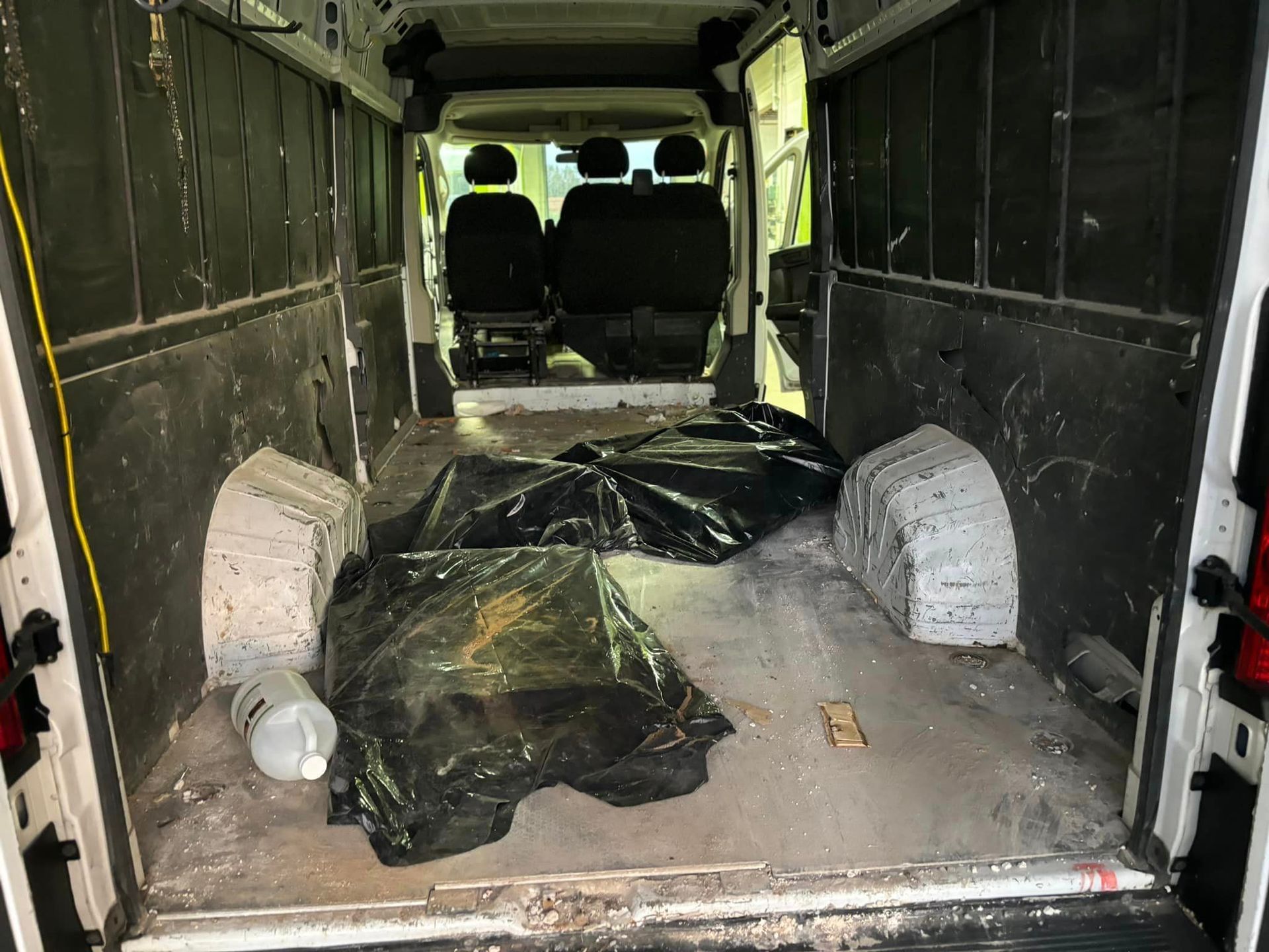 The inside of a white van with a black tarp on the floor.