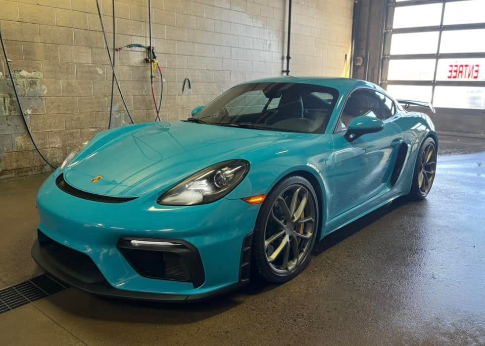 A blue porsche boxster gt4 is parked in a garage.