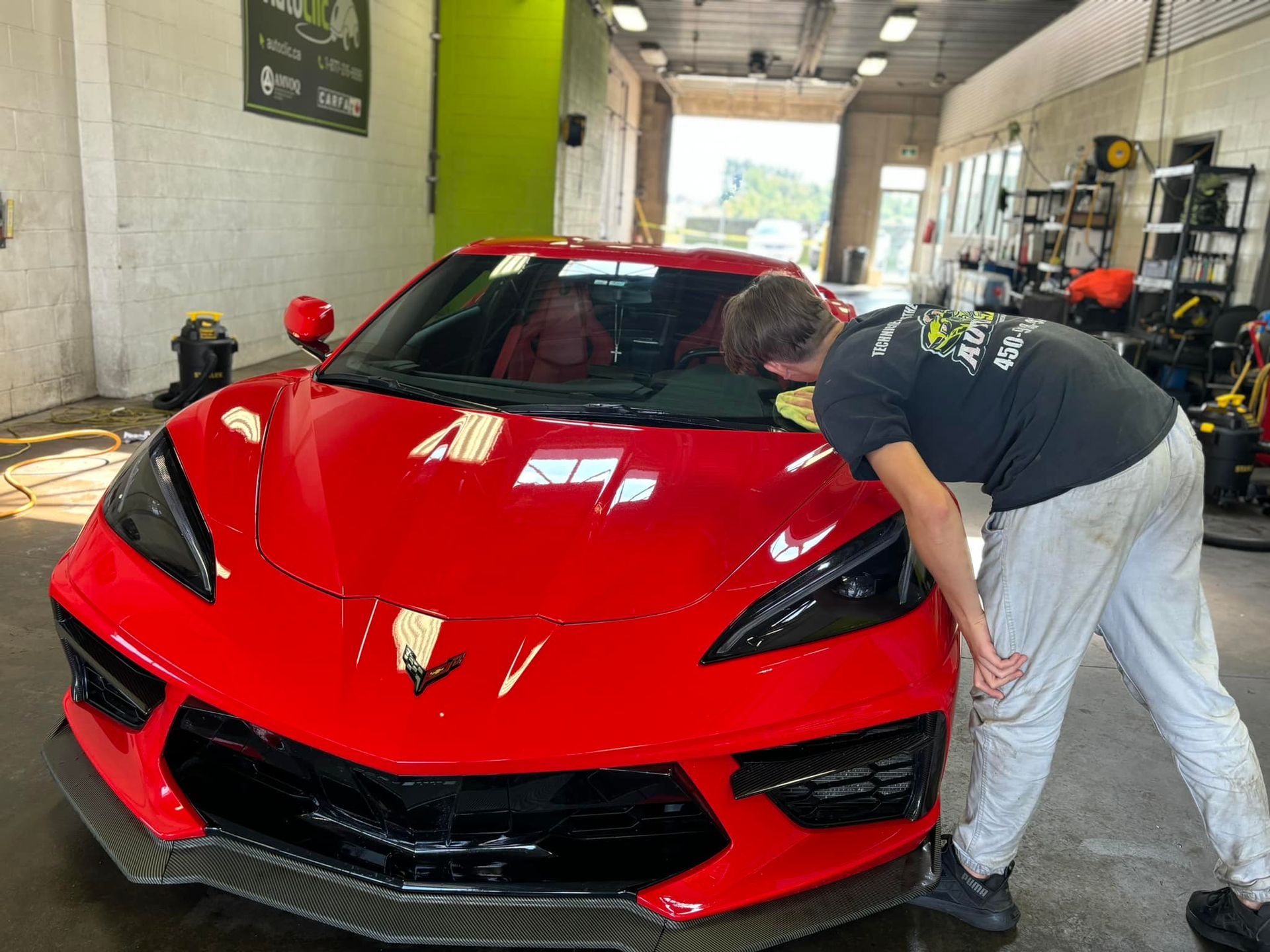 A man is working on a red sports car in a garage.