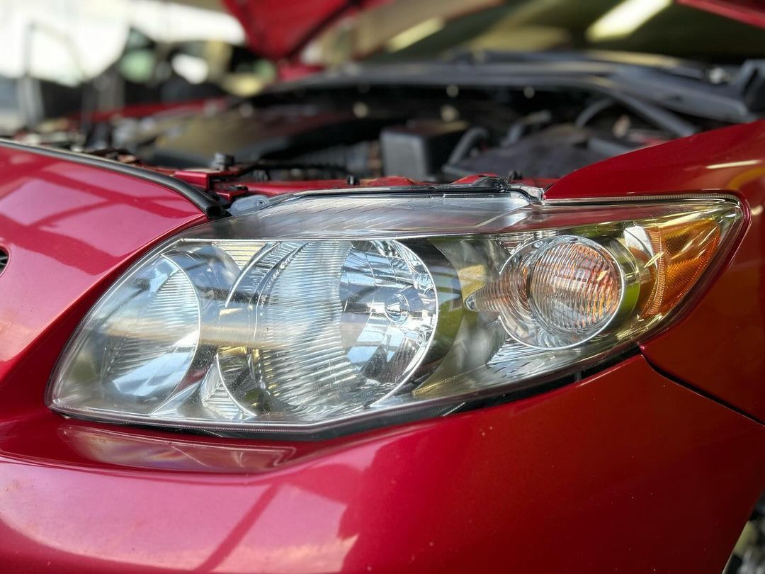 Un gros plan du phare d'une voiture rouge avec le capot ouvert.