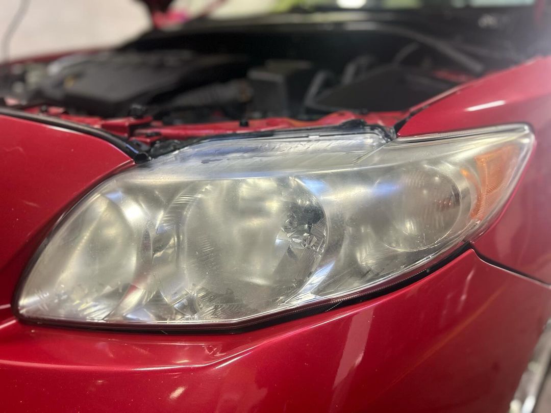 Un gros plan du phare d'une voiture rouge avec le capot ouvert.