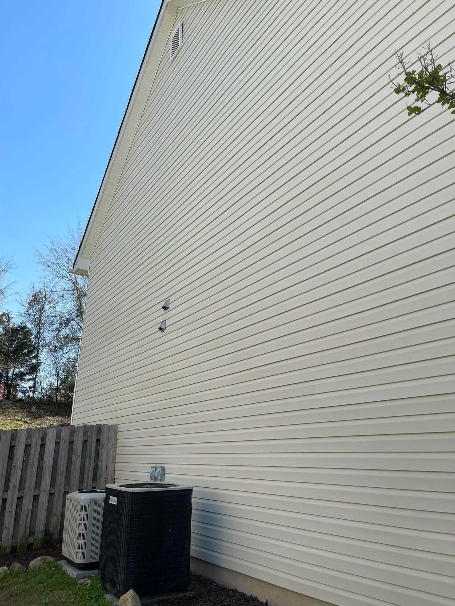 Light beige vinyl siding on the side of a house, featuring prominent circular melted patterns from sunlight reflection.