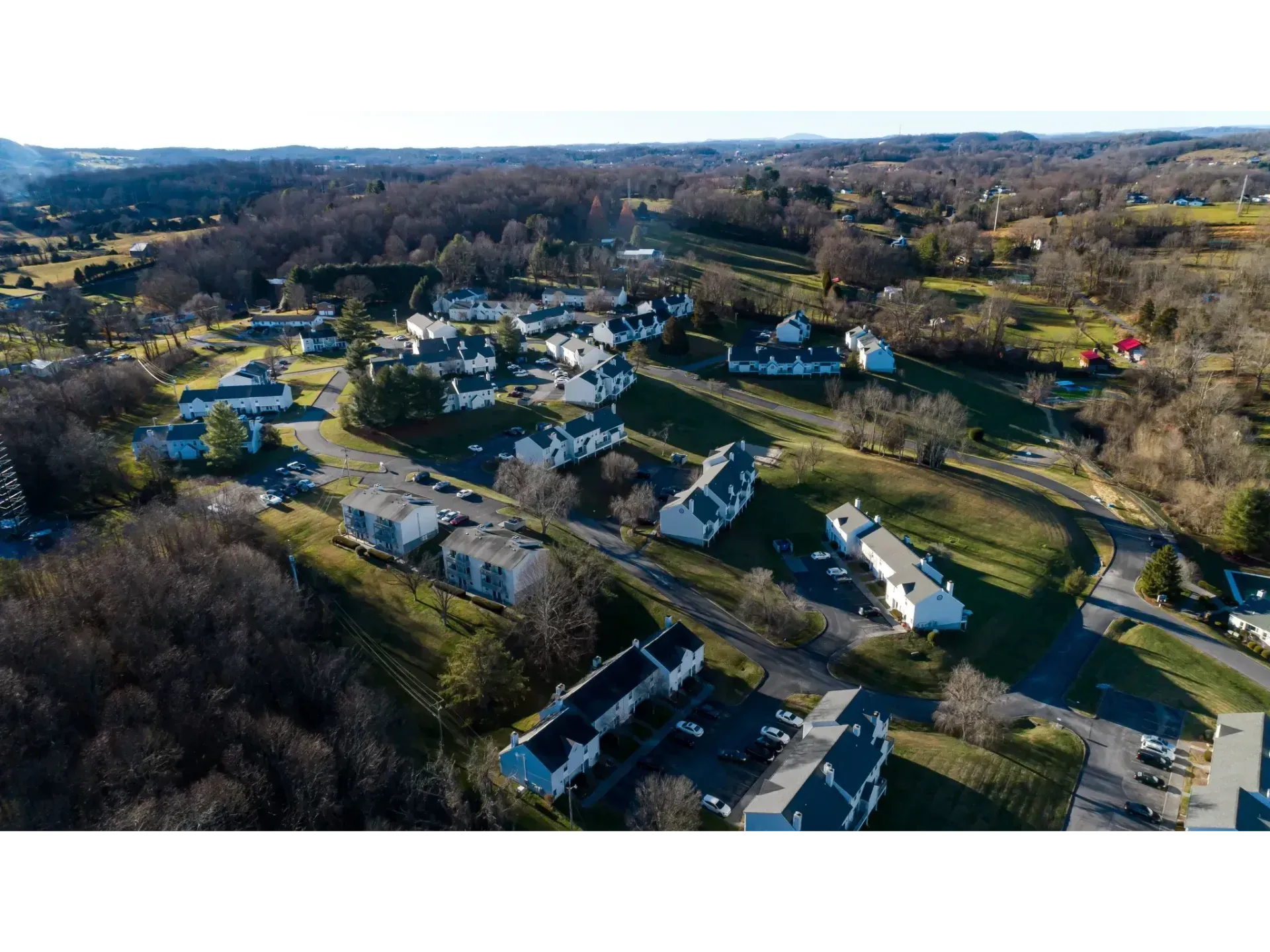 Aerial view of a small suburban neighborhood with houses, roads, and leafless trees