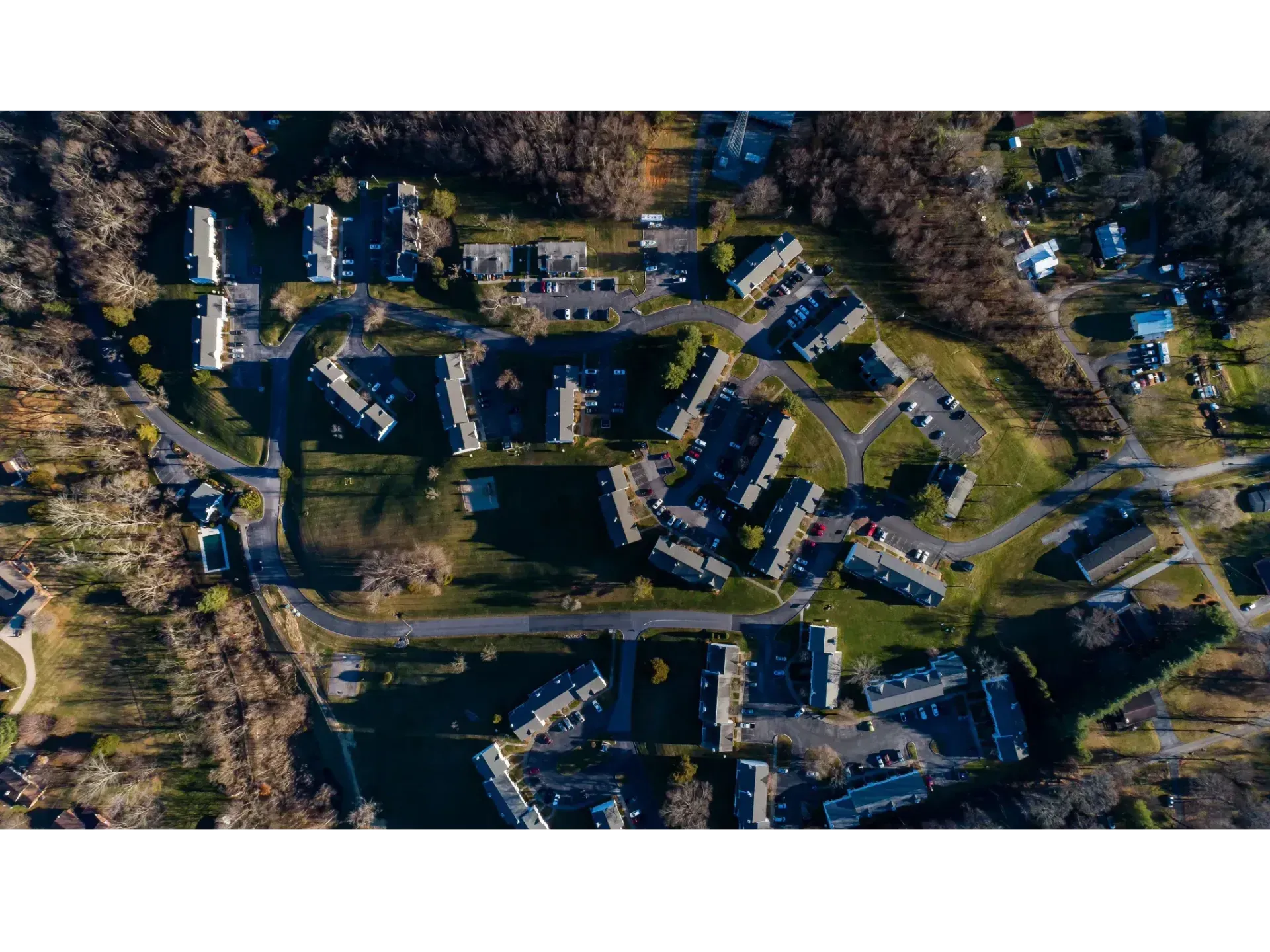 Aerial view of a residential neighborhood with houses, roads, and trees around a central pond