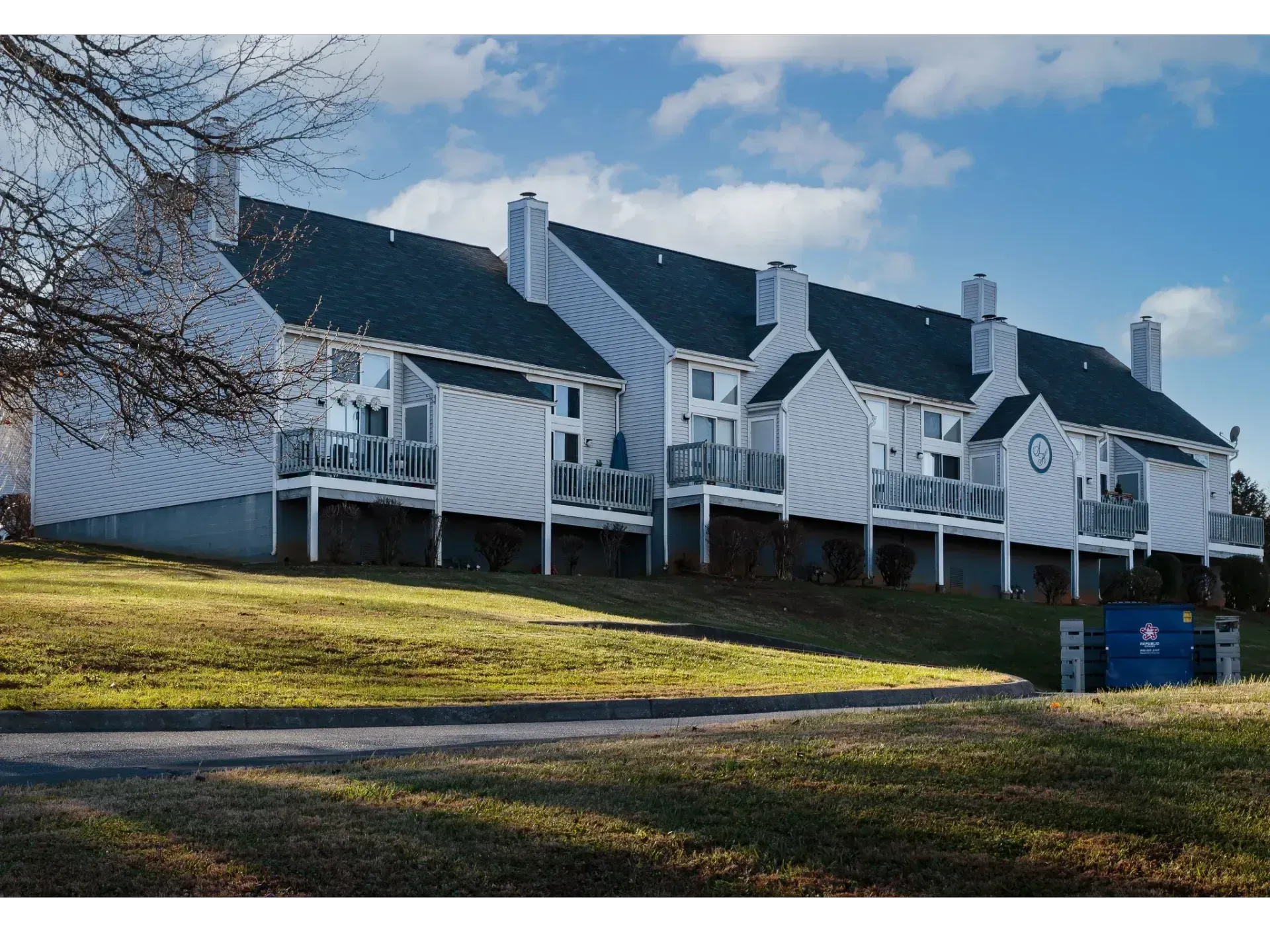White houses with dark roofs on a grassy hillside under a partly cloudy blue sky