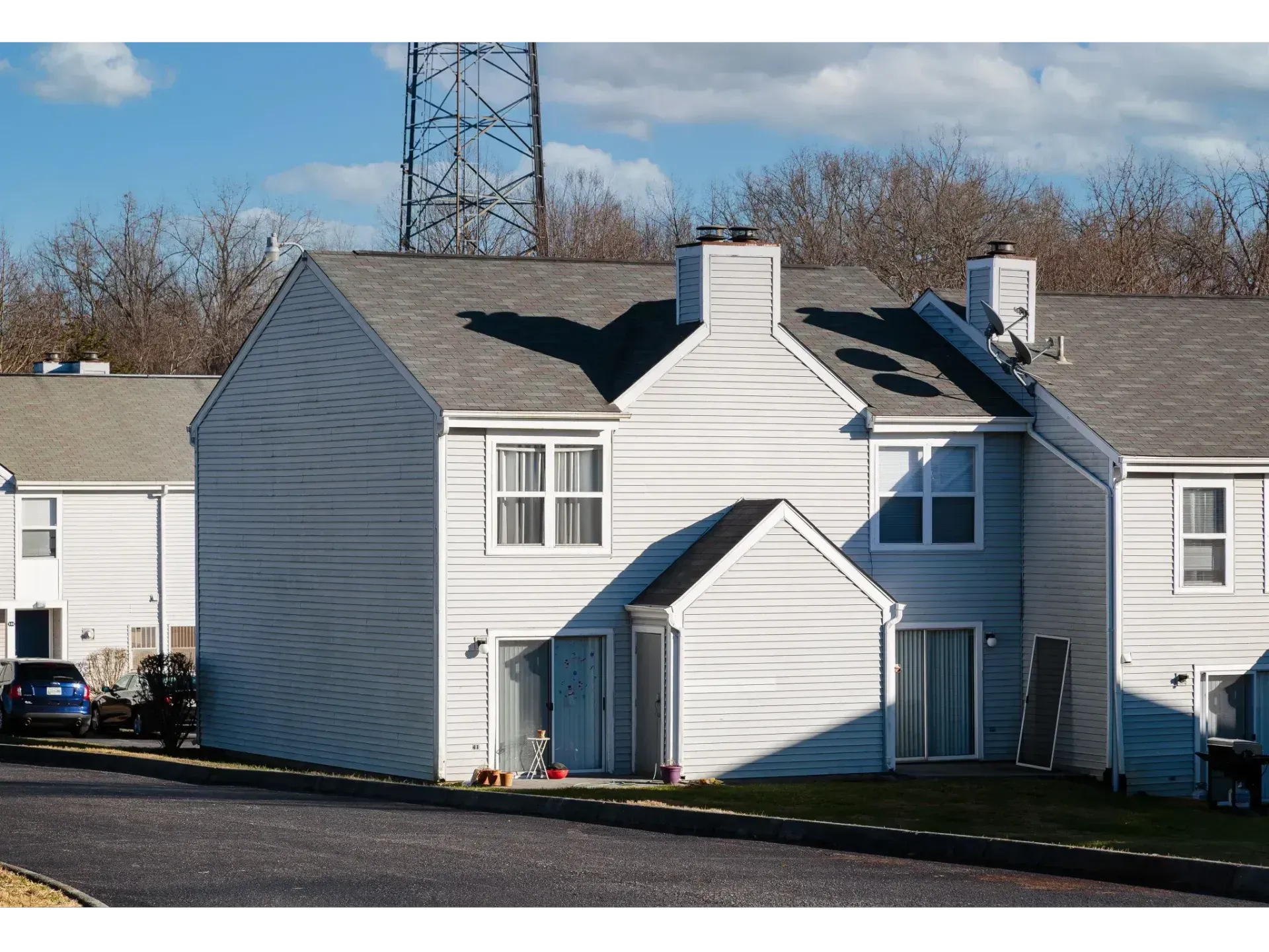 White townhouse-style apartment building with gray roof and chimneys on a sunny day