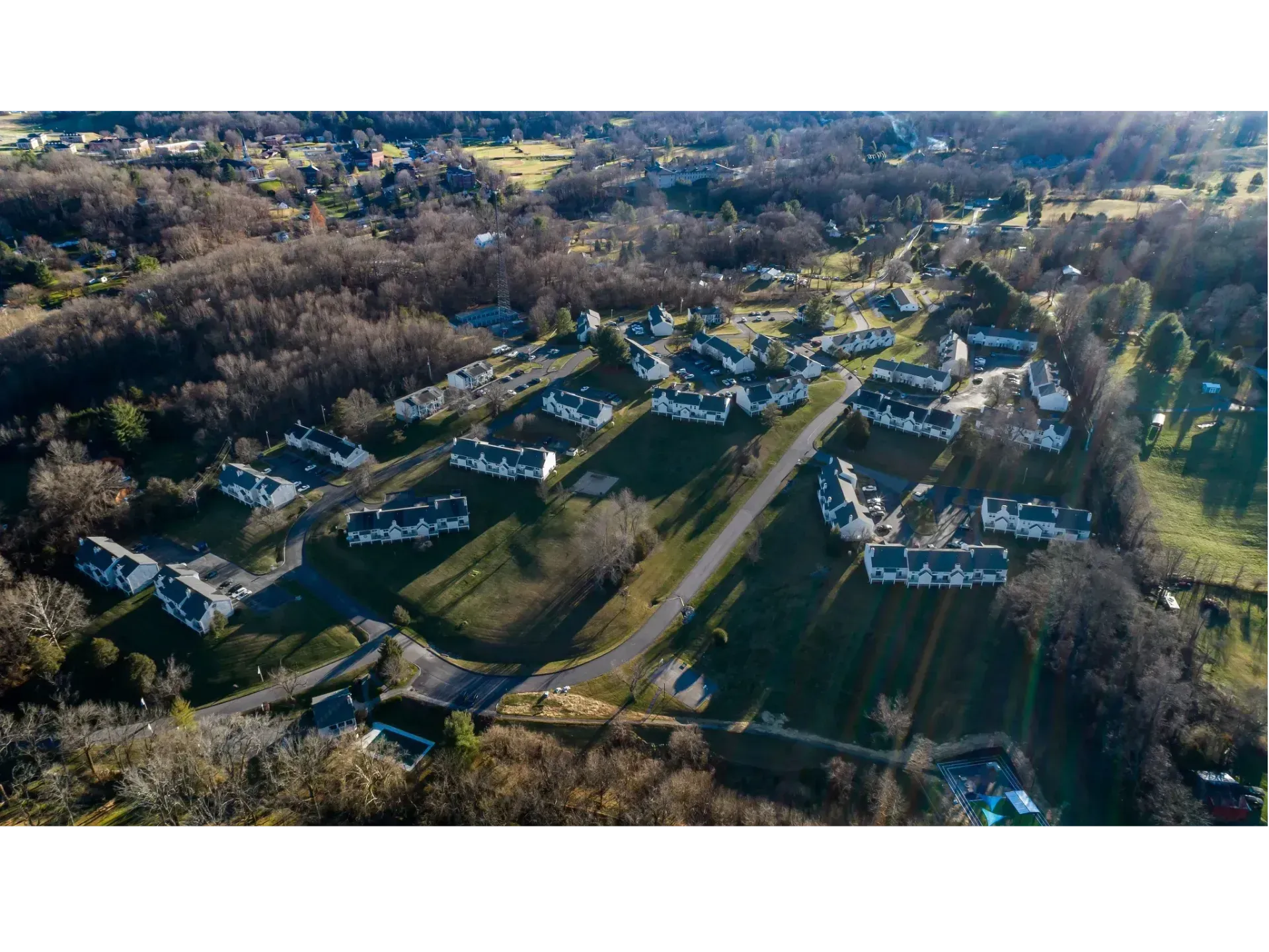 Aerial view of a suburban neighborhood with houses, roads, and trees in late autumn