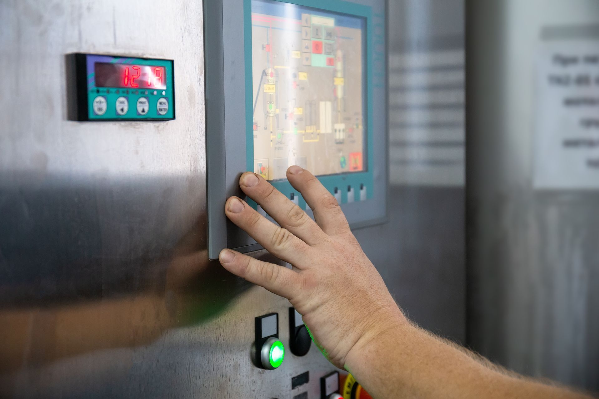 Hand touching control panel screen, likely for industrial equipment.