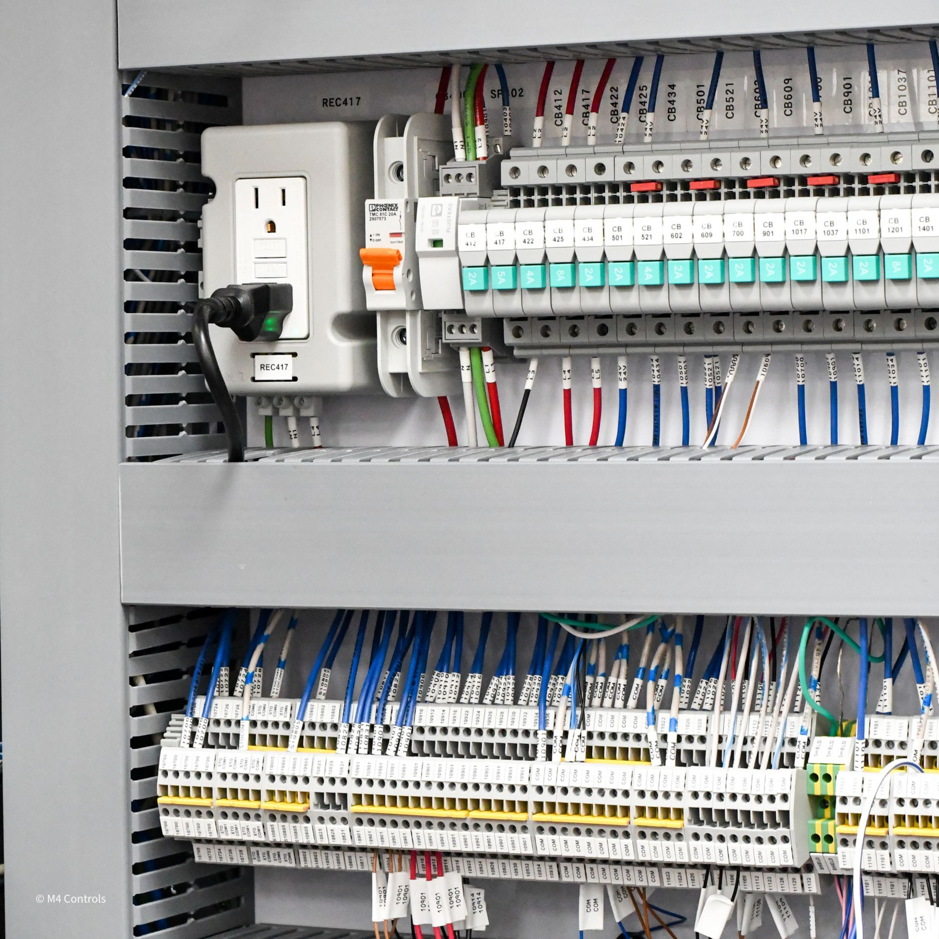 Electrical panel with wires and terminal blocks. White outlet and circuit breaker visible.
