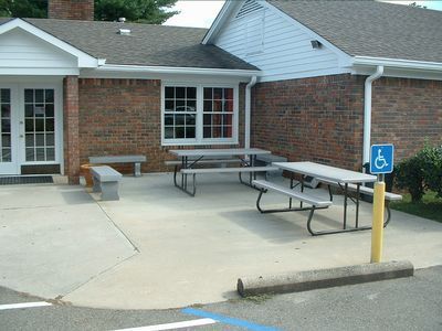 Accessible ramp and bench seating outside a brick building with a handicap parking sign.