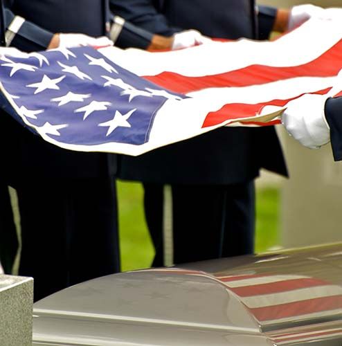 People holding a folded U.S. flag during a military or memorial ceremony