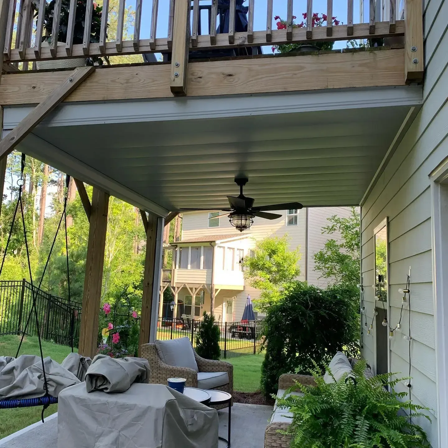 A white aluminum under-deck ceiling that includes a hardscaping design, support pillars, a jacuzzi, and outdoor lighting.