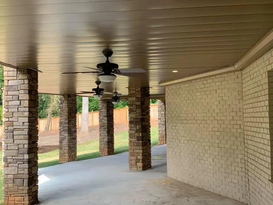 Brown vinyl under-deck system that includes a hardscaping design, three ceiling fans, and outdoor lighting.