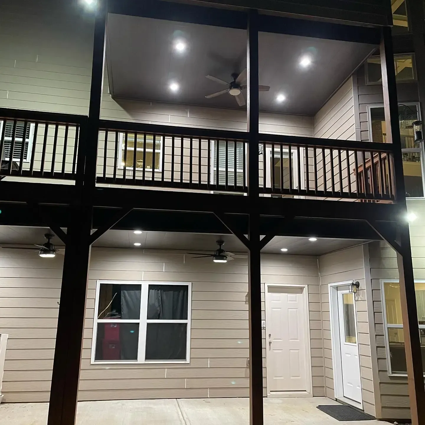 White aluminum under-deck system that includes a hardscaping design, two ceiling fans, and outdoor lighting.