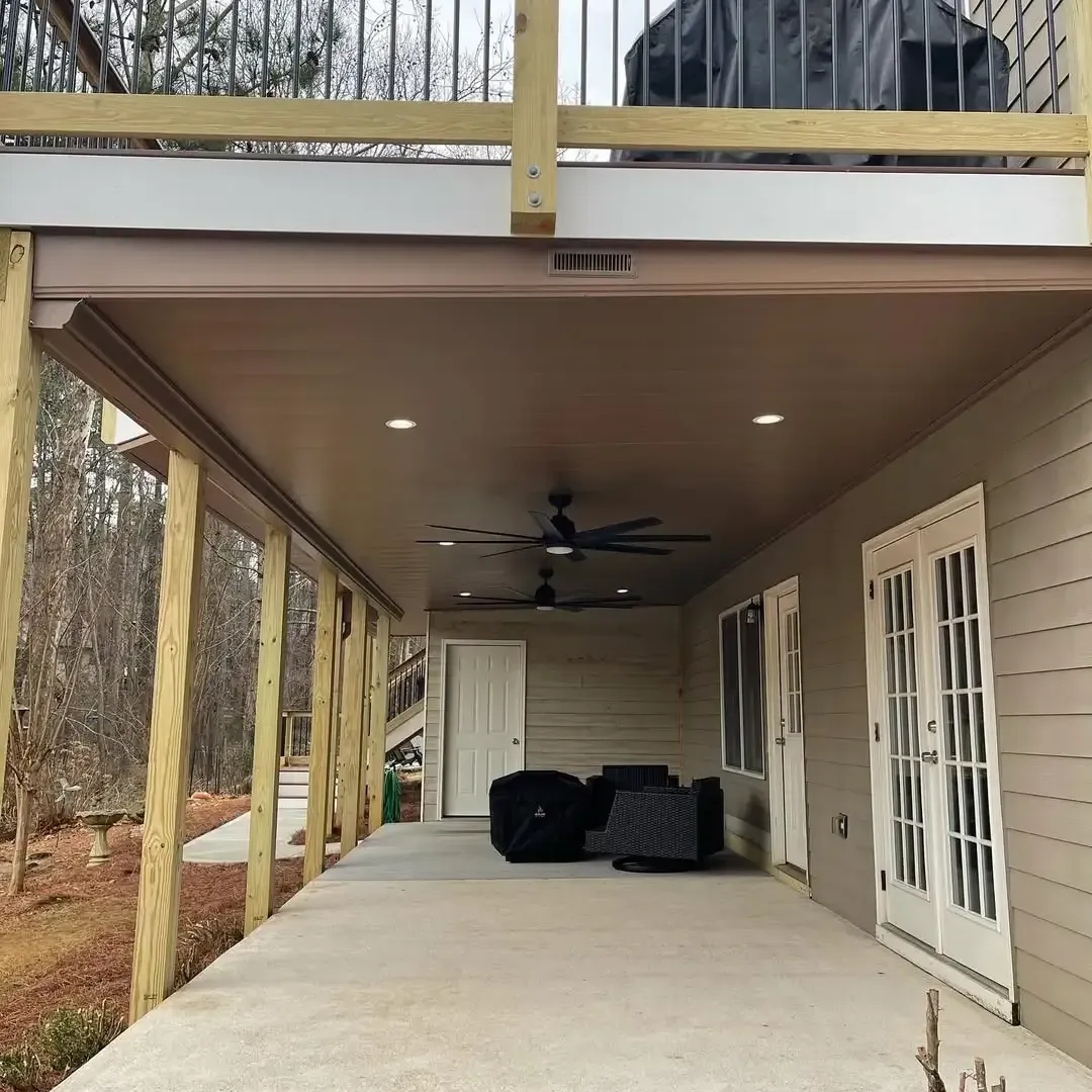 A white aluminum under-deck ceiling that includes a hardscaping design, support pillars, a jacuzzi, and outdoor lighting.