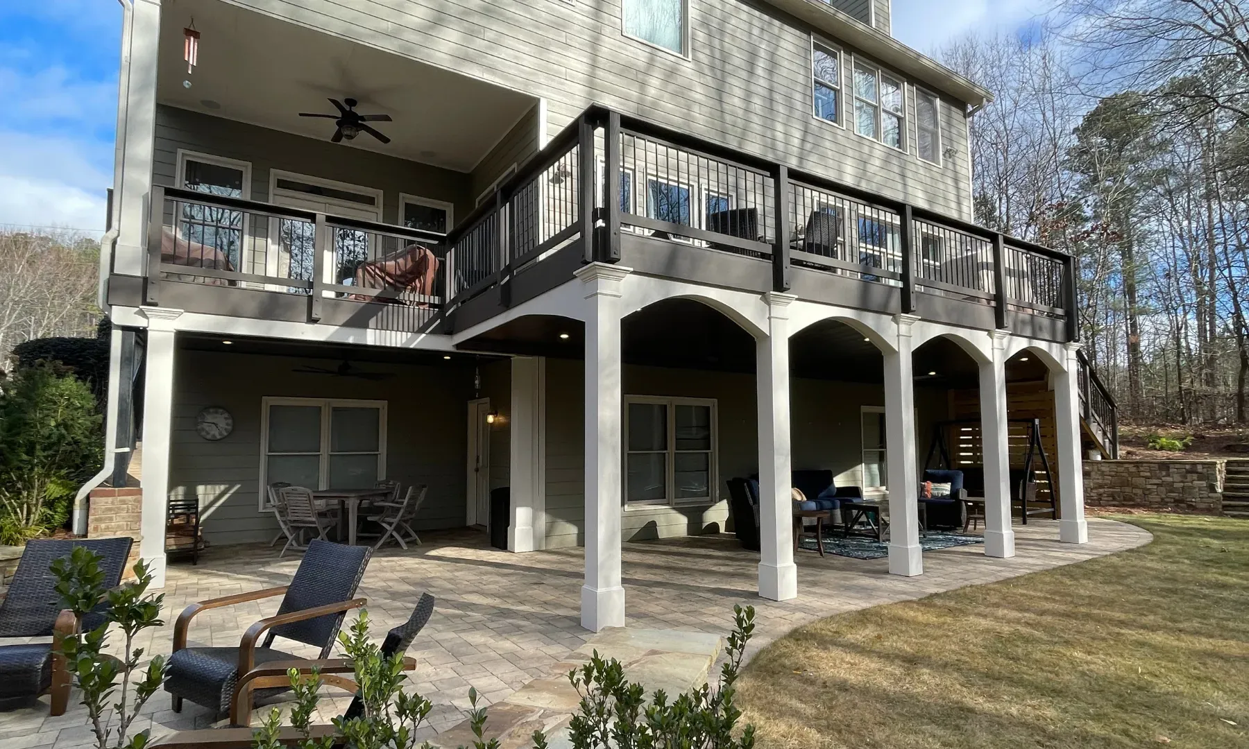Under deck patio design with added features such as ceiling fans, LED lighting, and paver patio flooring.
