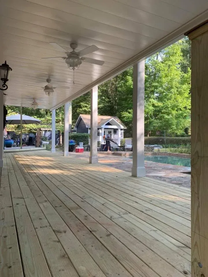 White aluminum under-deck ceiling that includes a hardscaping design, two ceiling fans, and outdoor lighting.
