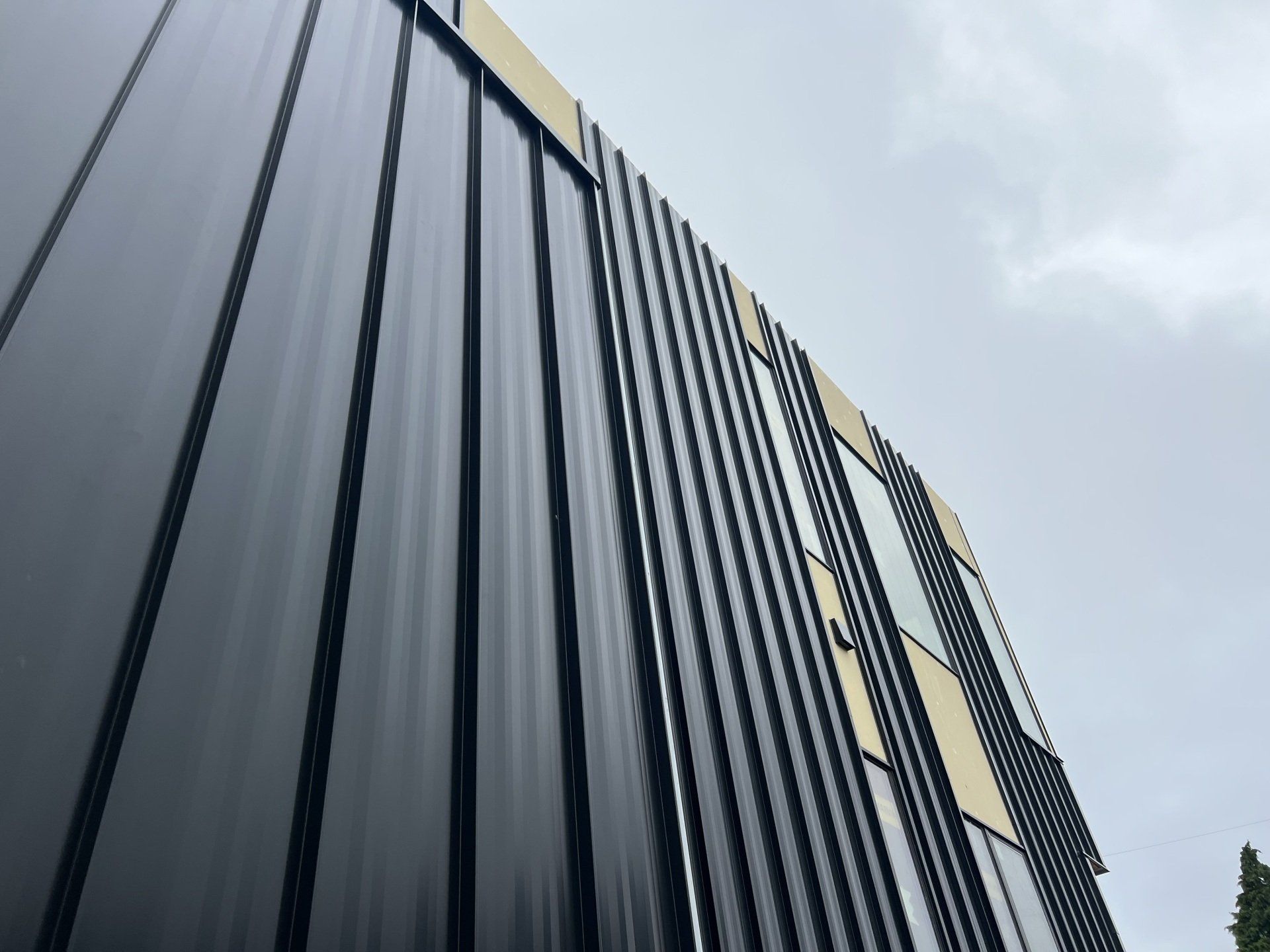 A black building with a lot of windows and a cloudy sky in the background.