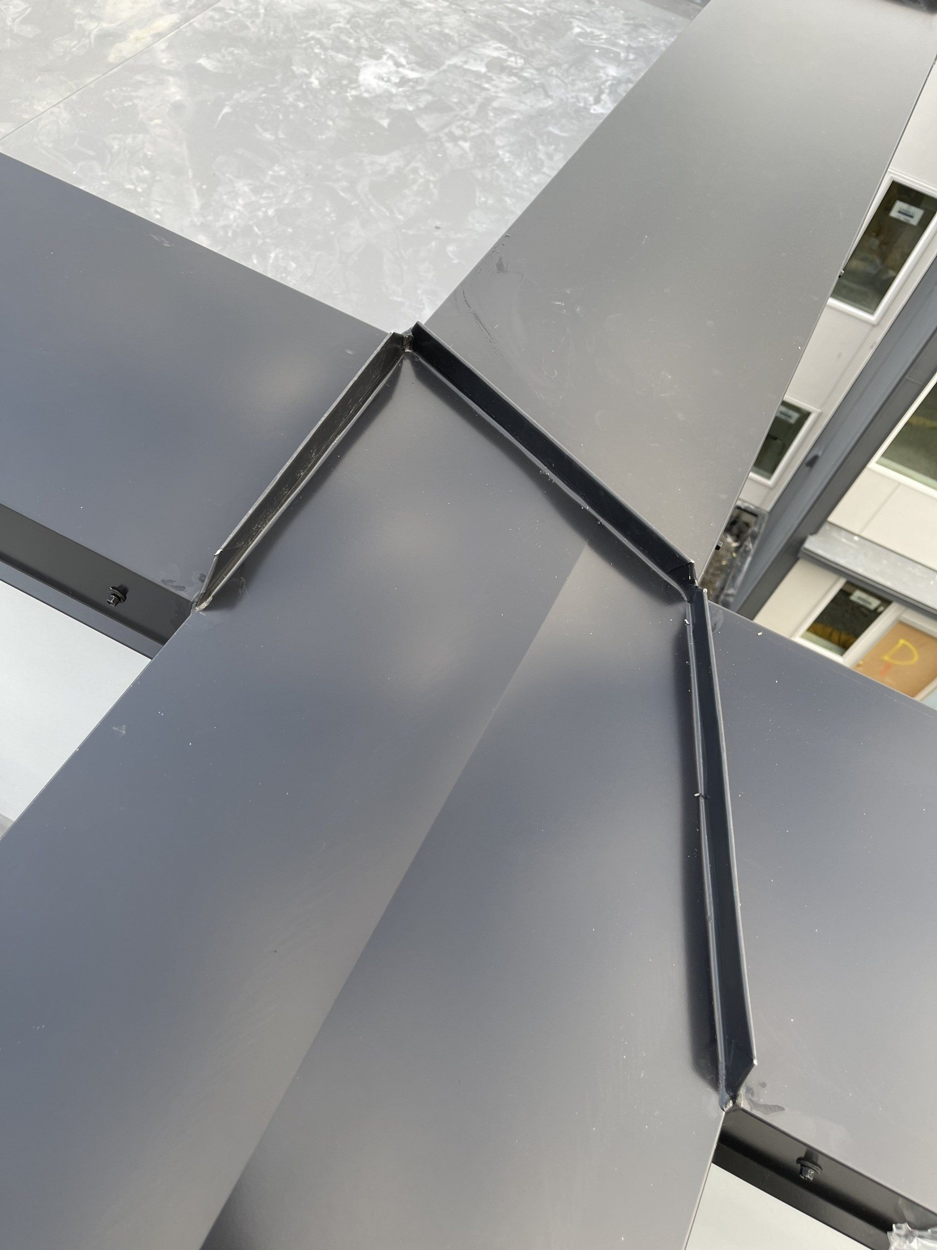 A close up of a metal roof with a corner that looks like a cross.