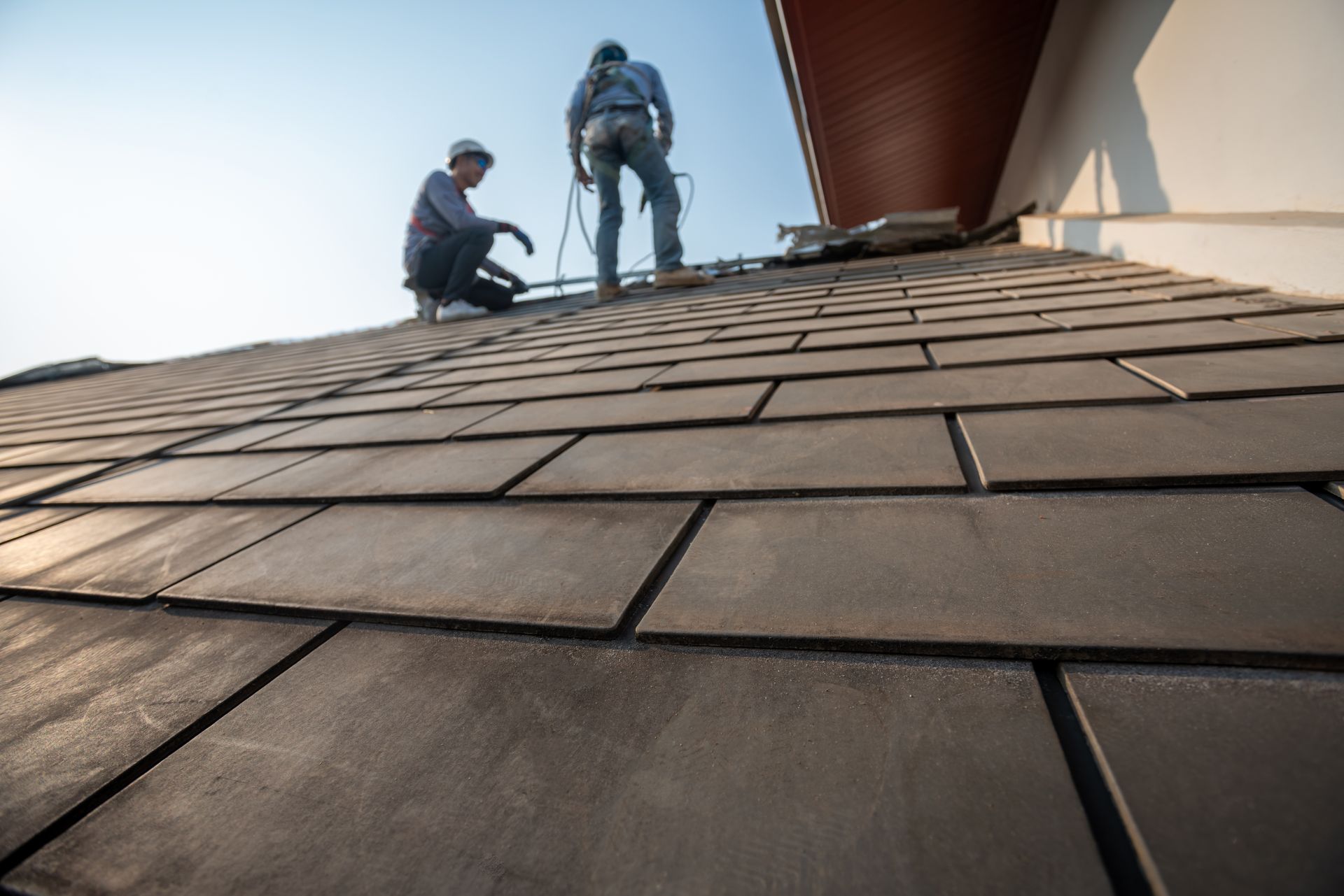 A professional team performing a residential roofing replacement with new dark shingles. A professional team performing a residential roofing replacement with new dark shingles.