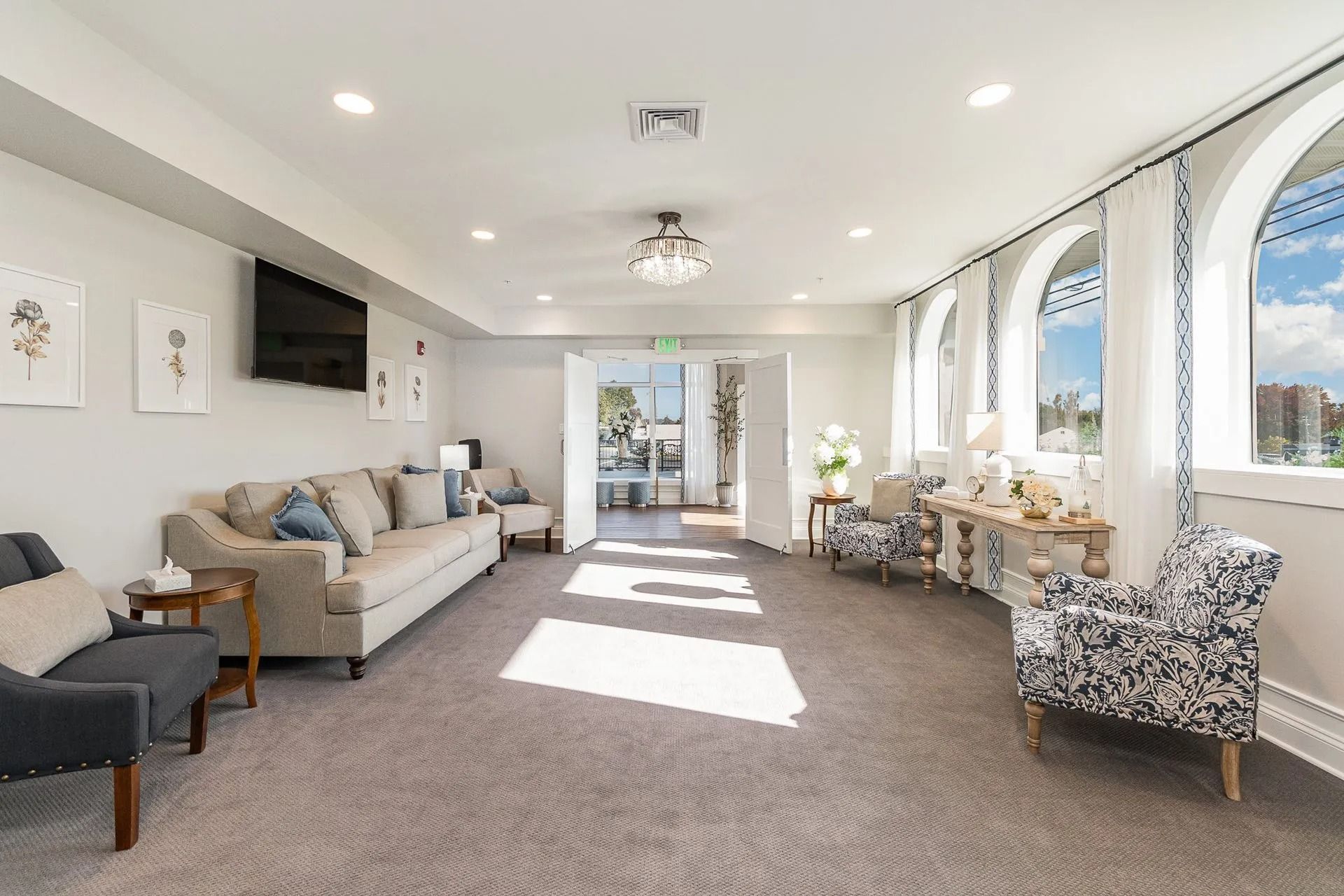 Bright waiting room with sofa, armchairs, and arched windows. Soft light, neutral colors.