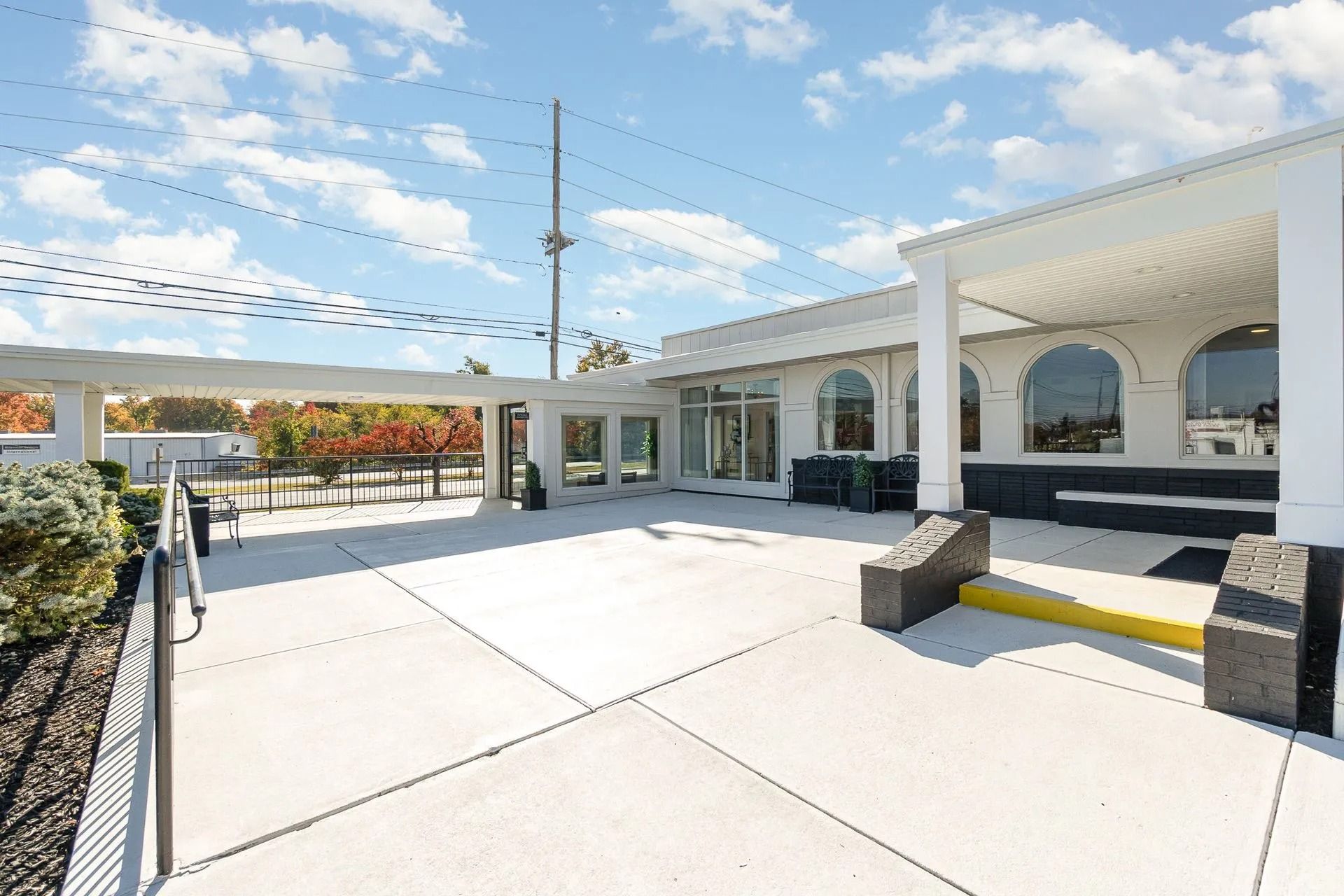 Exterior of a white building with an outdoor patio, blue sky with clouds.