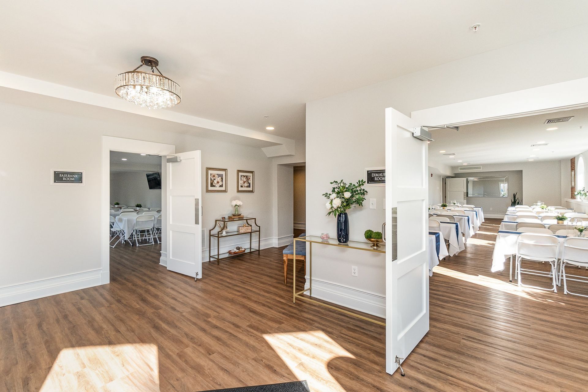 Bright interior with open doorways leading to event spaces, featuring tables and decorations.