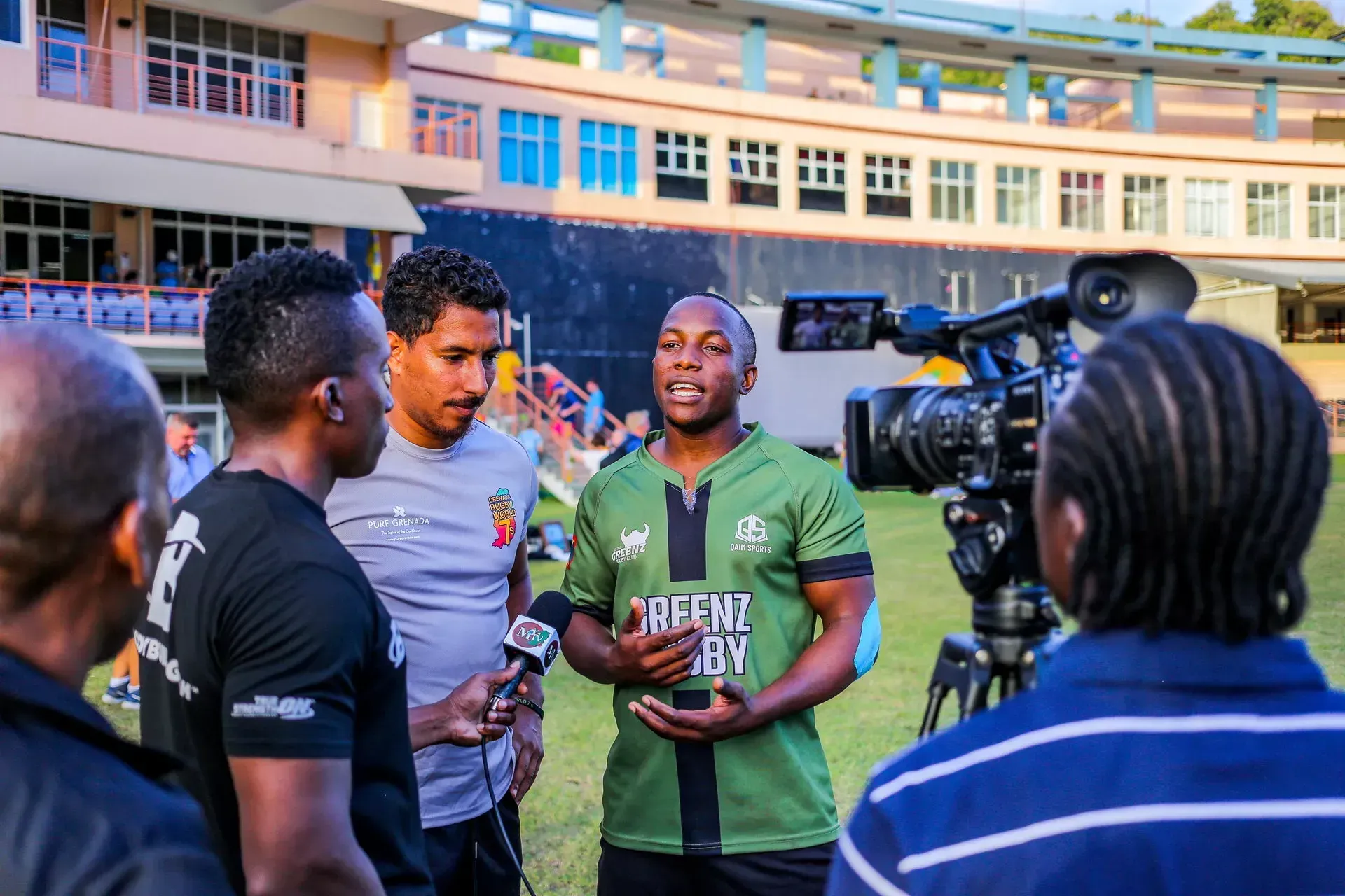 People gathered for an interview outdoors, with a cameraman filming two speakers in front of a building.