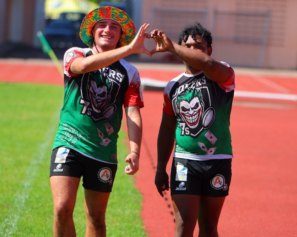 Two runners in green jerseys high-five on a track field after a race