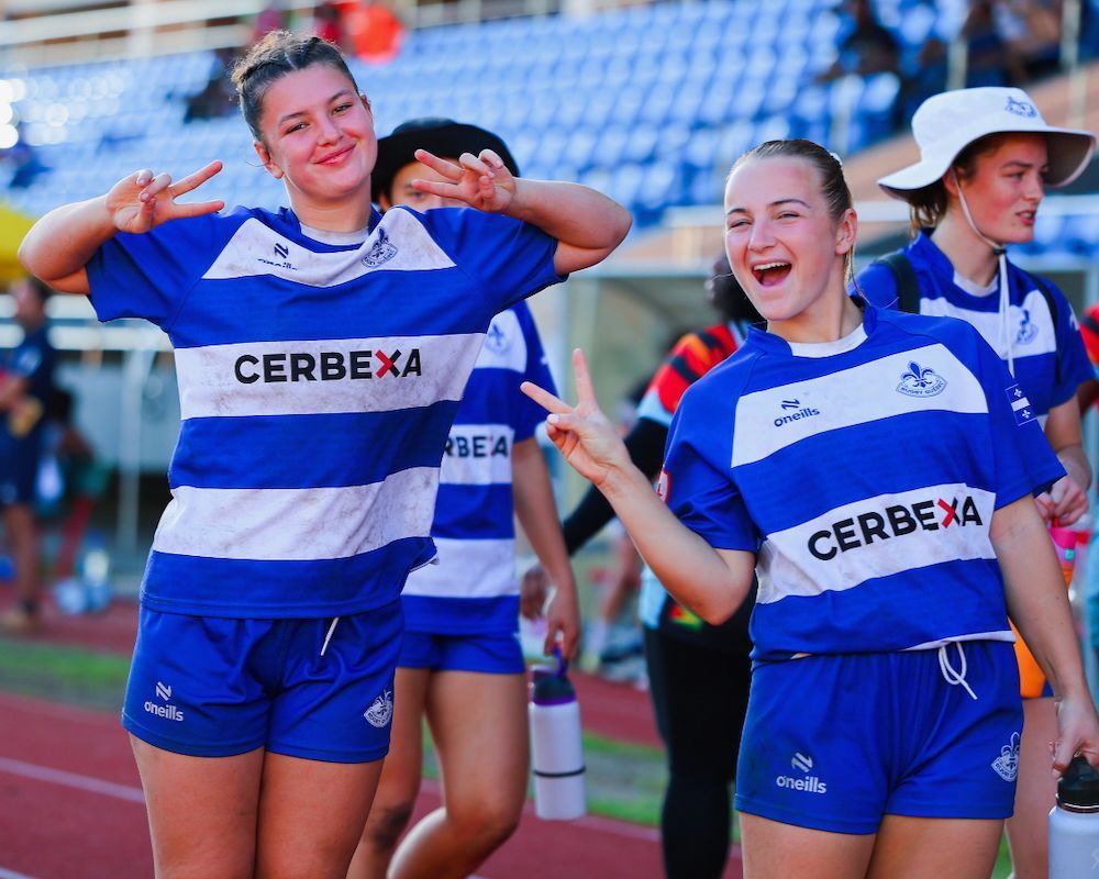 Three athletes in blue-and-white CERBEXA uniforms smiling on a sports field
