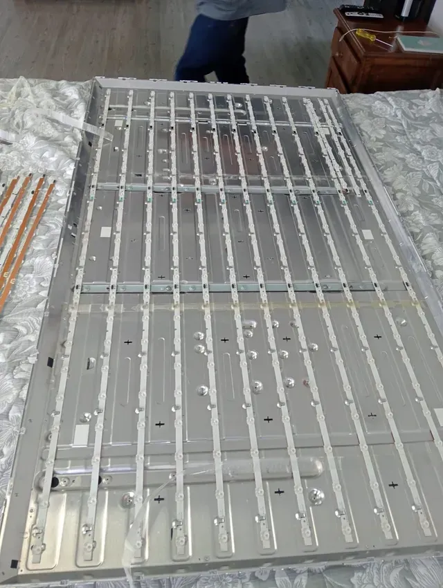 Reja o puerta de metal blanco colocada sobre una superficie estampada, con las piernas de una persona visibles al fondo.
