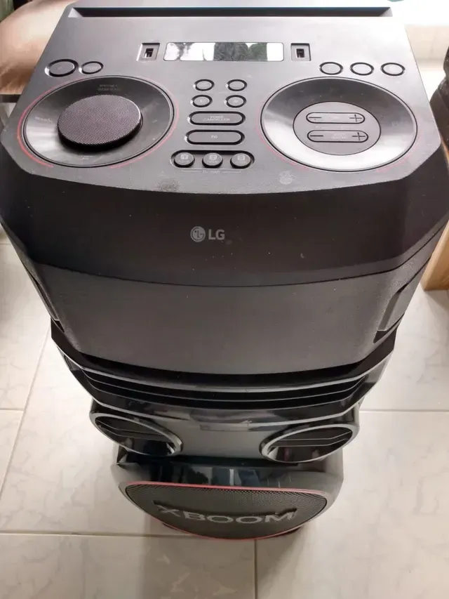 Aire acondicionado de torre LG negro con controles superiores y salida de aire frontal, mostrado en interiores sobre un suelo de baldosas.