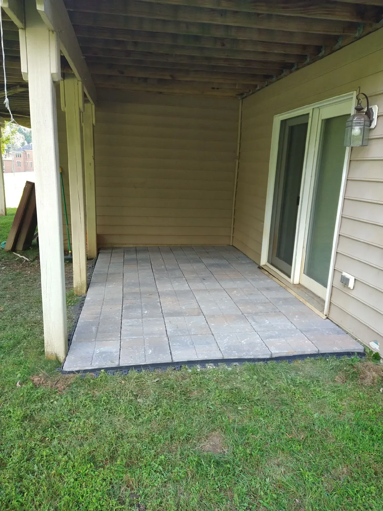 Covered patio with beige siding and tiled floor beside a grassy yard