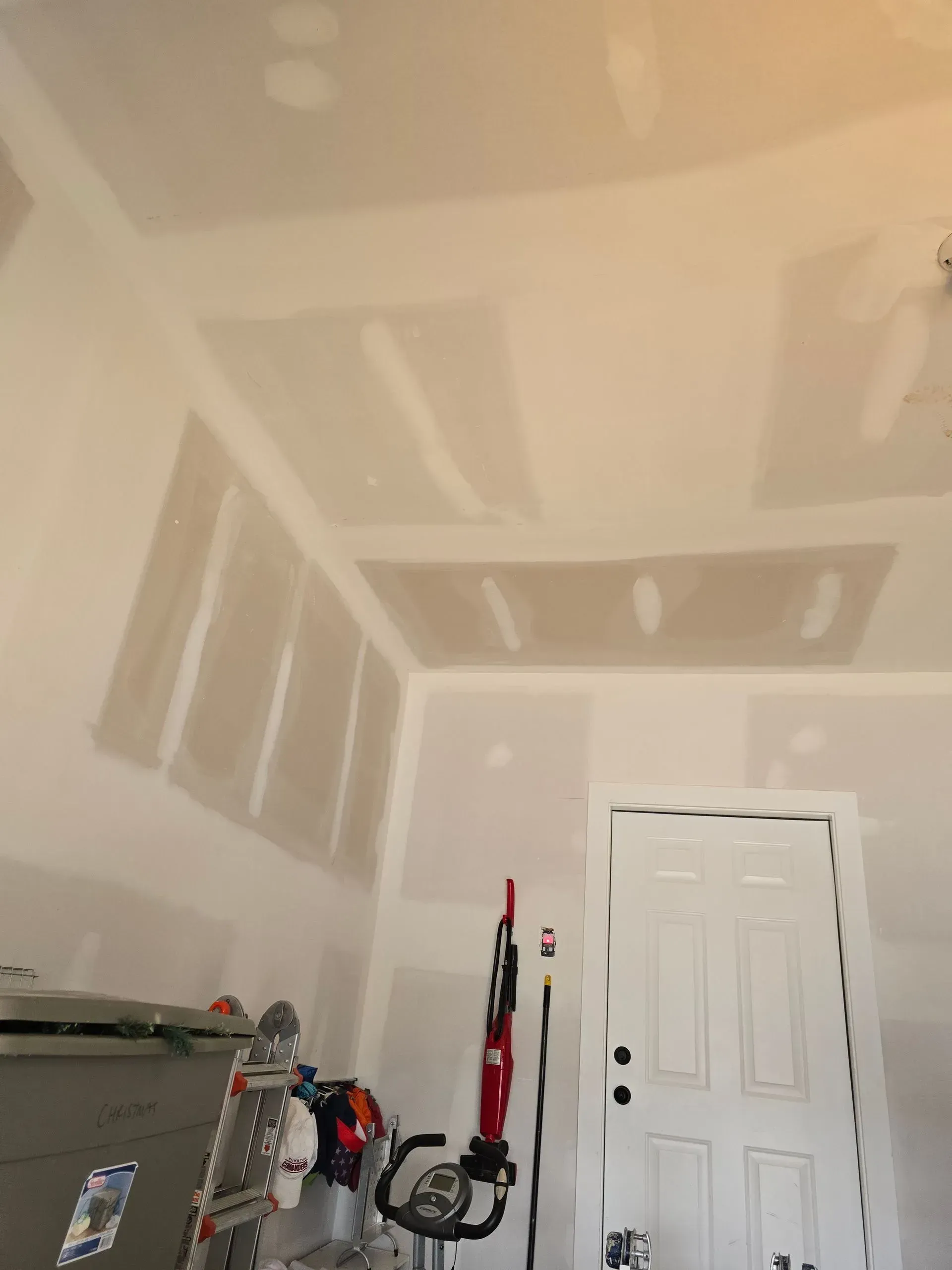 Unfinished room with taped drywall patches, closet door, and cleaning tools leaning against the wall