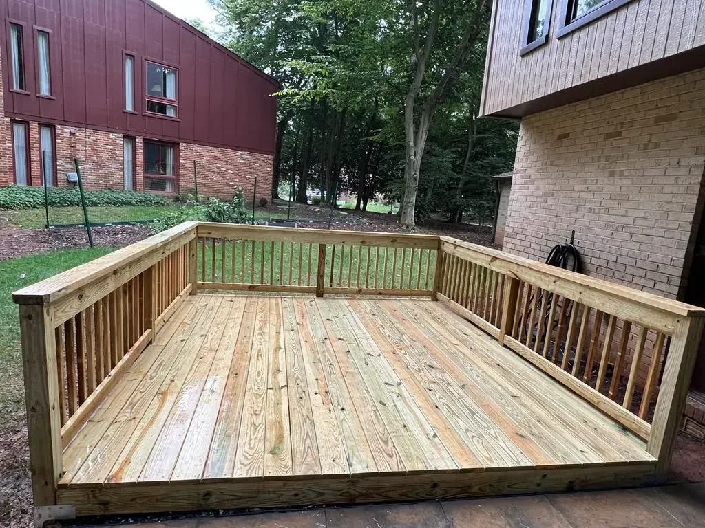 Wooden accessibility ramp/deck between apartment buildings, with railings and a level landing.