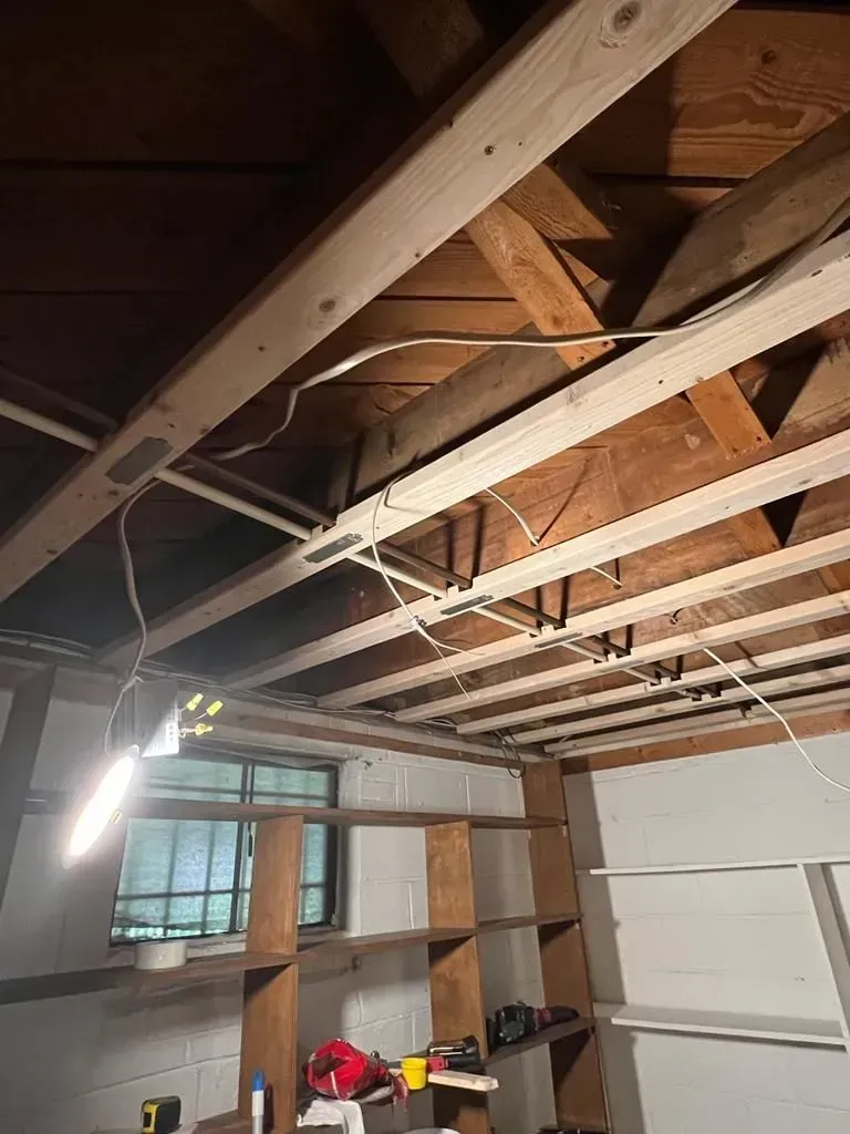 Partially finished room with exposed ceiling beams, window, and construction tools on the floor