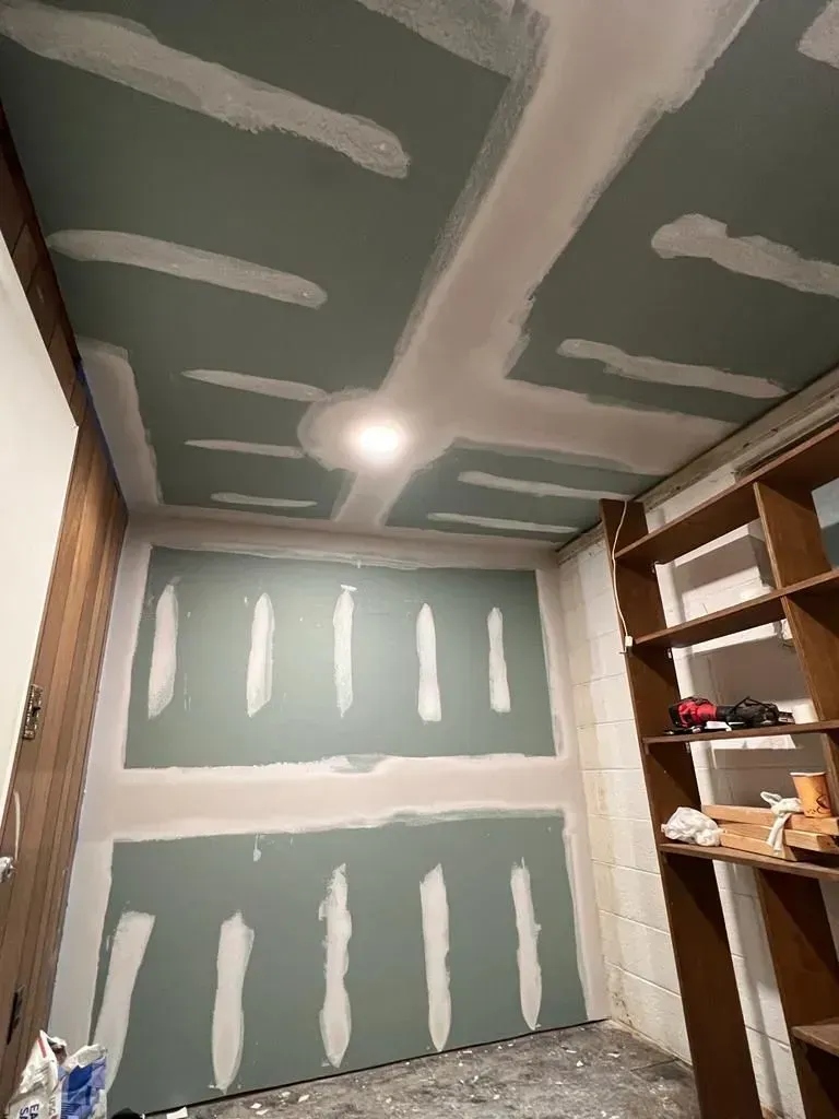 Small unfinished closet or storage room with drywall seams, ceiling light, and shelves on the right.