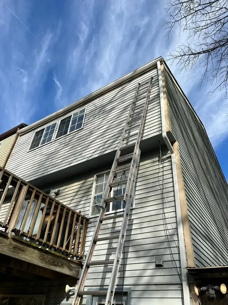 Modern gray house with wood deck under a blue sky, viewed from below