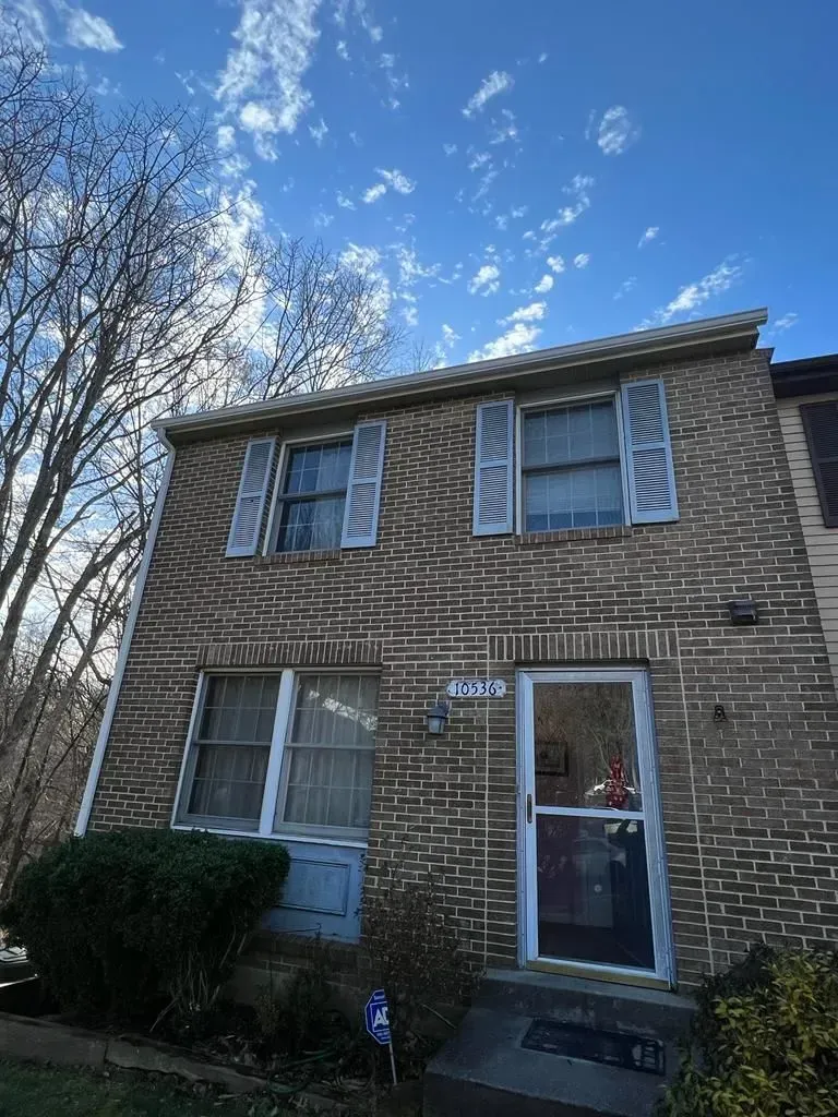 Two-story brick house with blue sky, bare trees, and a front door with a glass storm door