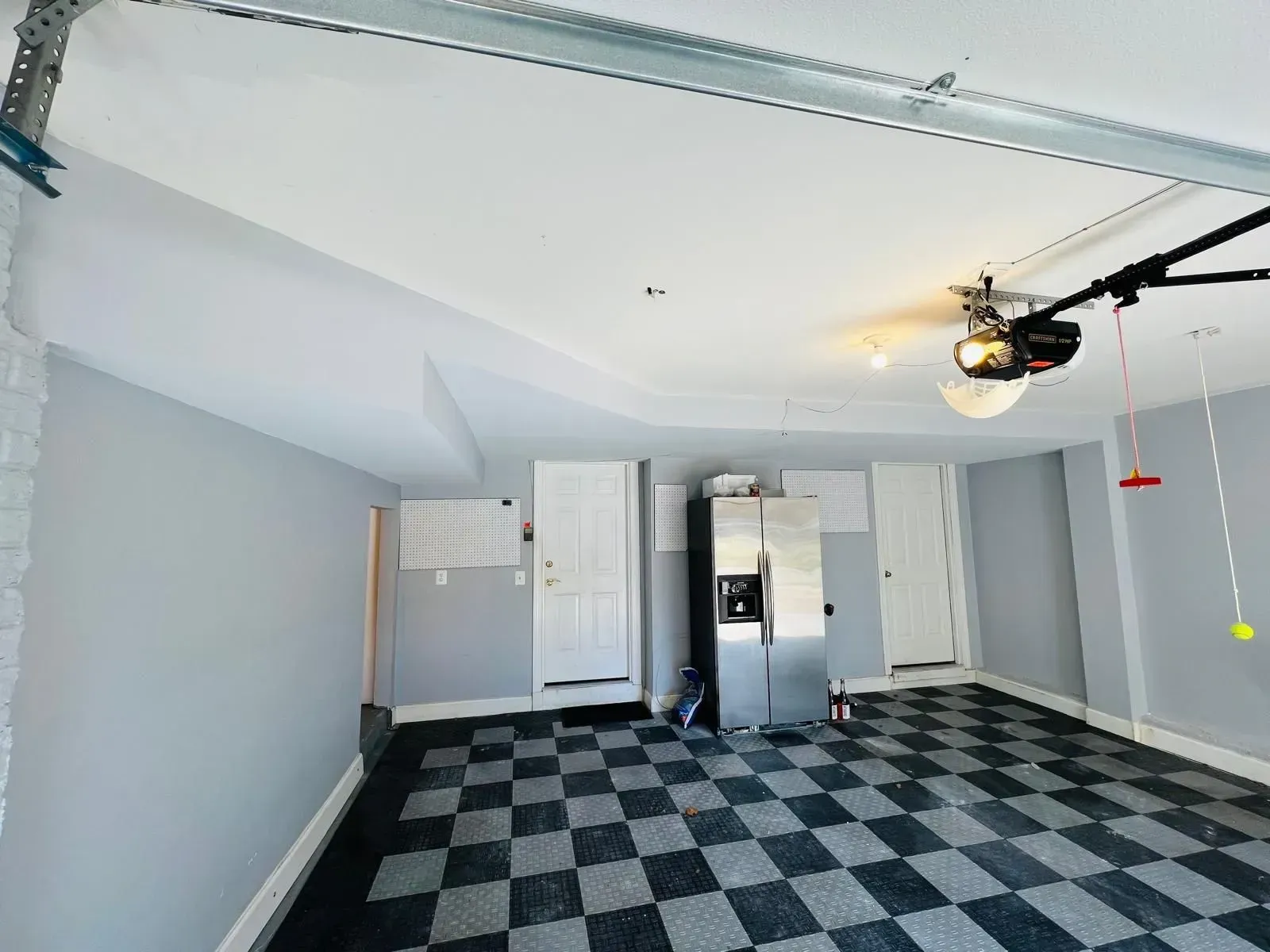 Empty garage with black-and-white checkered floor and overhead door opener