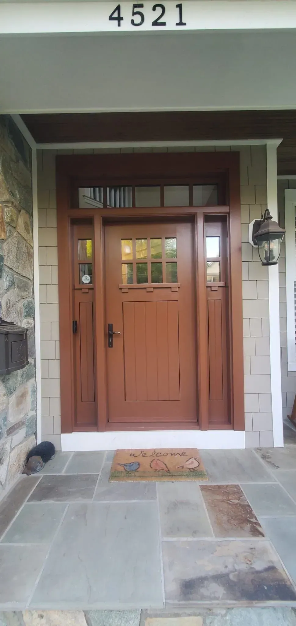 Front entrance with wooden double doors, stone walkway, and house number 4521 above the doorway