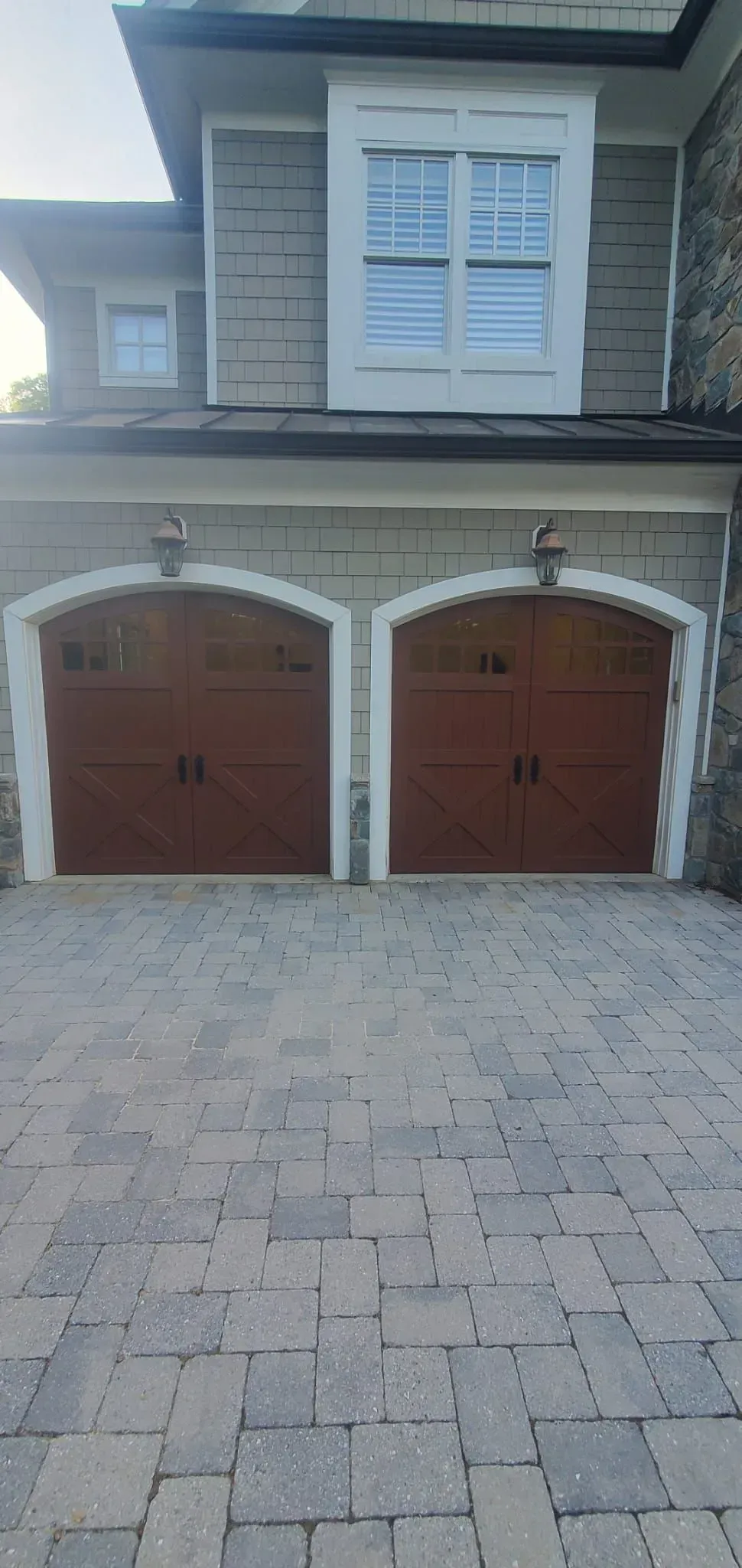 Two-car garage with brown doors and a paved driveway under a stucco house facade