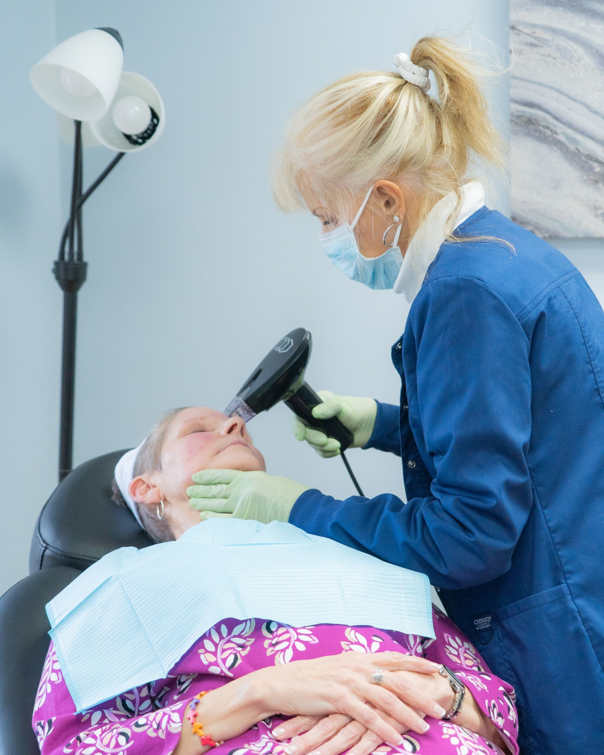Medical professional performing a facial procedure on a patient in a clinic setting.